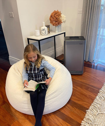 Girl Reading Indoors with NuWave OxyPure Air Purifier - Ensuring Clean and Safe Air