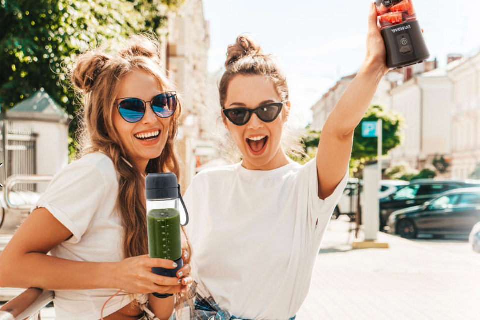 Two girls happily smiling while using the Nuwave On-The-Go Portable Blender
